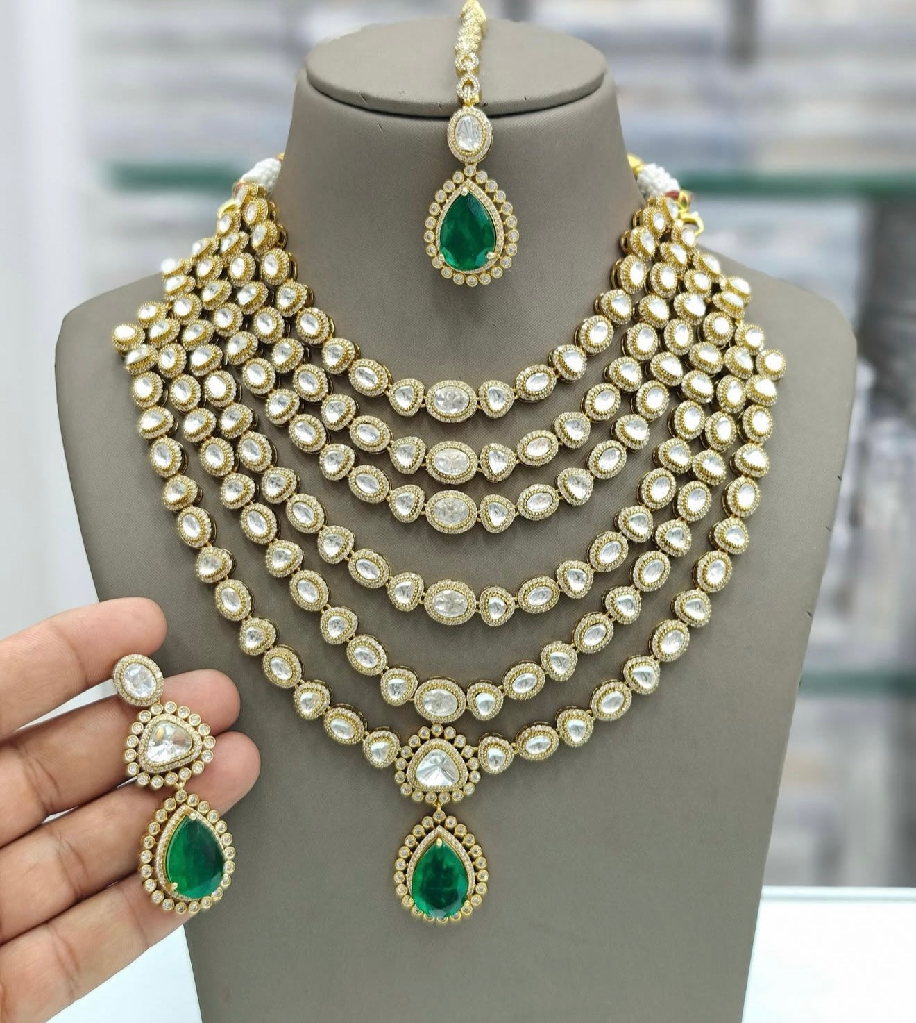 This is a layered Panchlada necklace featuring kundan stones and emerald beads.