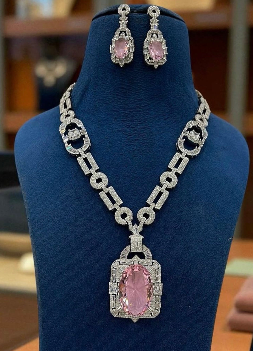 This is a square-shaped, silver-toned, American diamond-studded necklace set with a pink stone