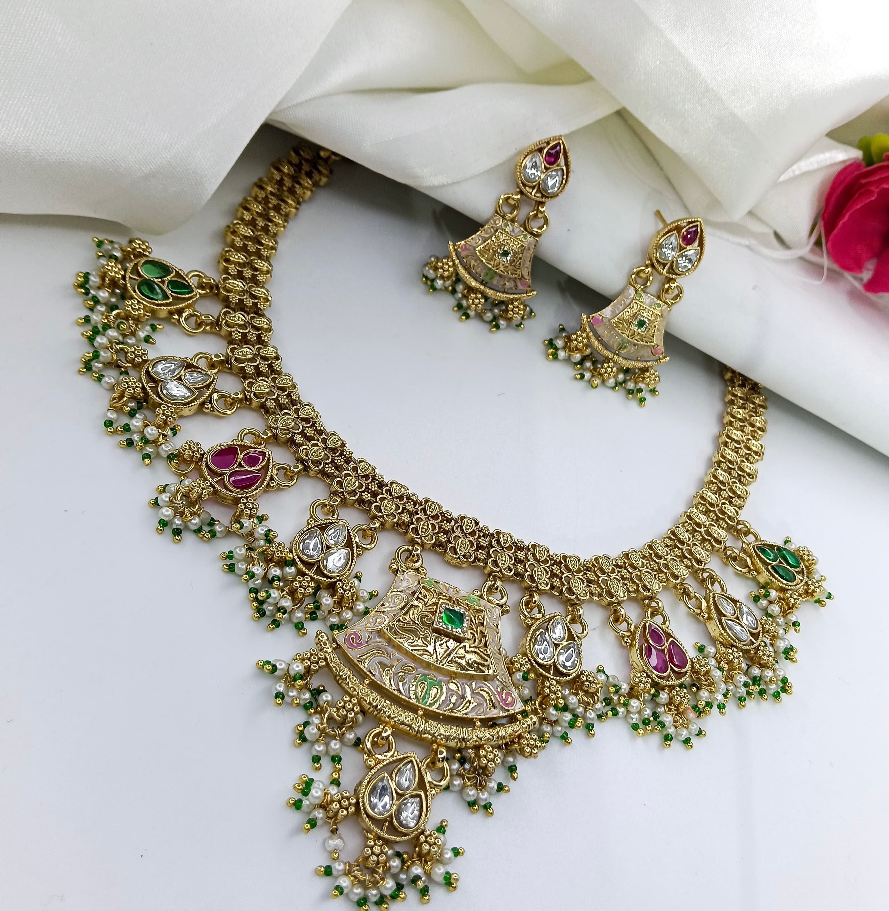 This is a gold-plated peacock design antique necklace set with matching earrings, featuring kundan stones, pearls, and colored beads.